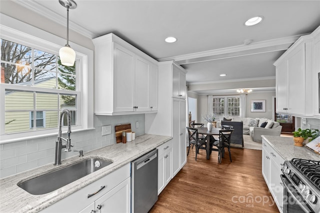 kitchen featuring a sink, wood finished floors, white cabinetry, appliances with stainless steel finishes, and crown molding