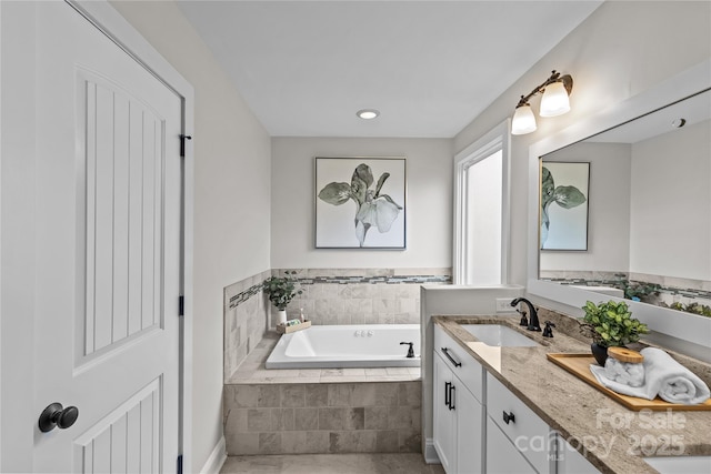 bathroom featuring double vanity, a garden tub, and a sink