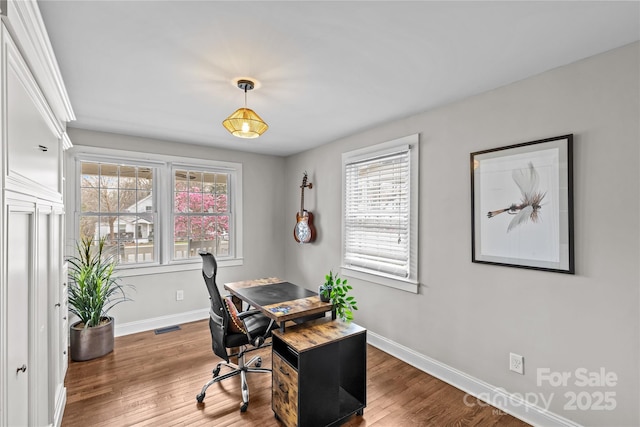 office area with a wealth of natural light, visible vents, baseboards, and wood finished floors