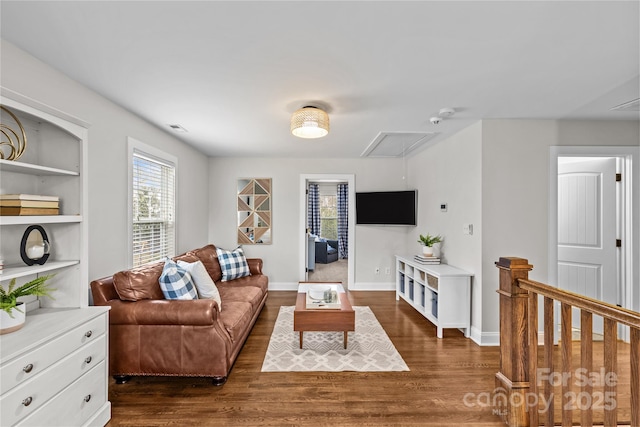 living room with visible vents, attic access, baseboards, and wood finished floors