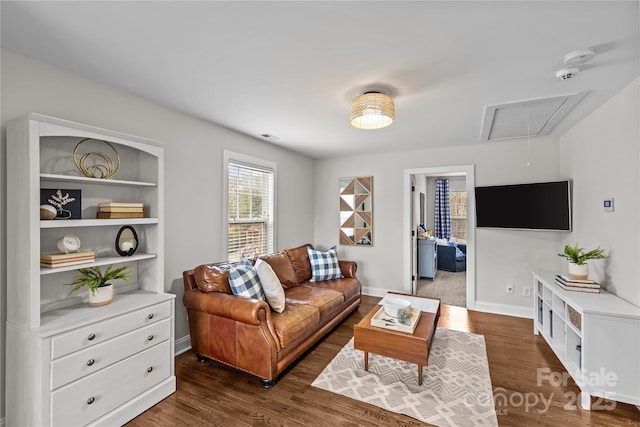 living room with baseboards, attic access, and wood finished floors