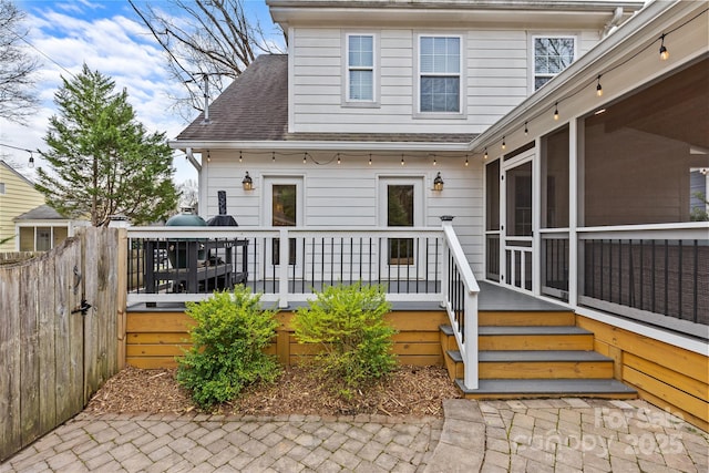 entrance to property featuring a deck, fence, and a shingled roof