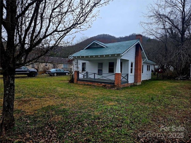 view of home's exterior with a yard, covered porch, and a chimney