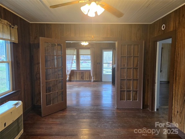 unfurnished dining area featuring wood finished floors, wood walls, and a healthy amount of sunlight