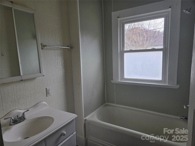 full bath with vanity, tile walls, and a healthy amount of sunlight