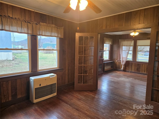 empty room with heating unit, wooden walls, and hardwood / wood-style flooring