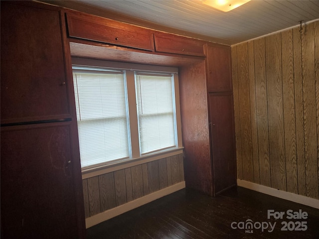 spare room featuring wood walls, baseboards, and dark wood-style flooring