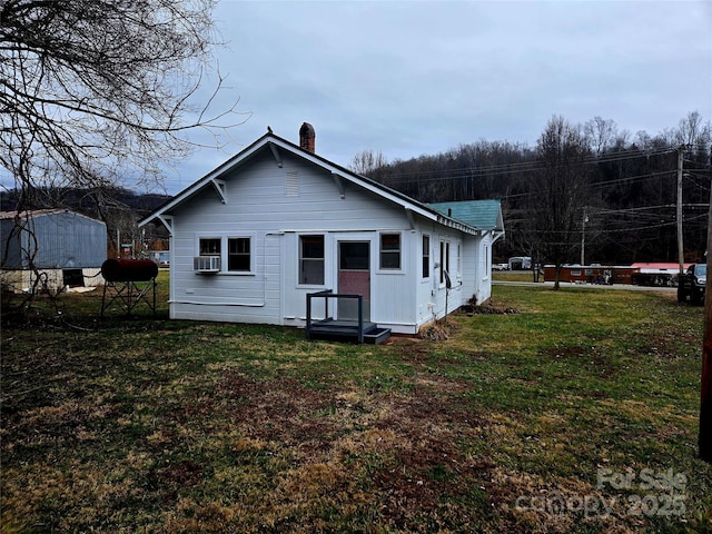 rear view of house featuring a lawn, cooling unit, and a chimney