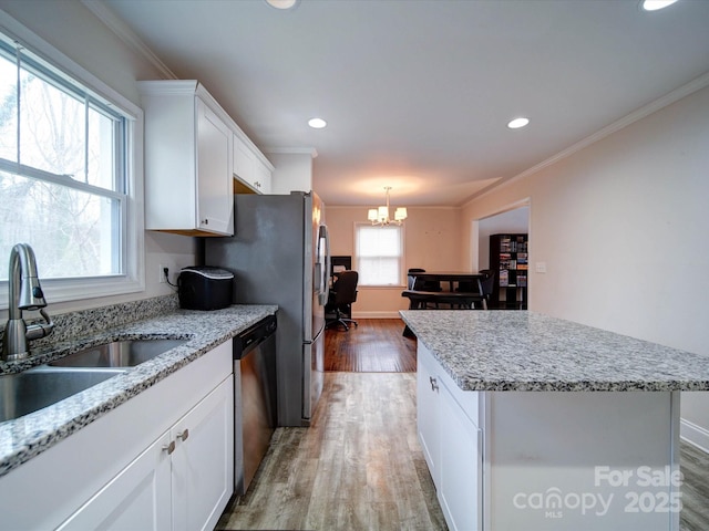 kitchen with a kitchen island, light wood-style flooring, a sink, dishwasher, and crown molding