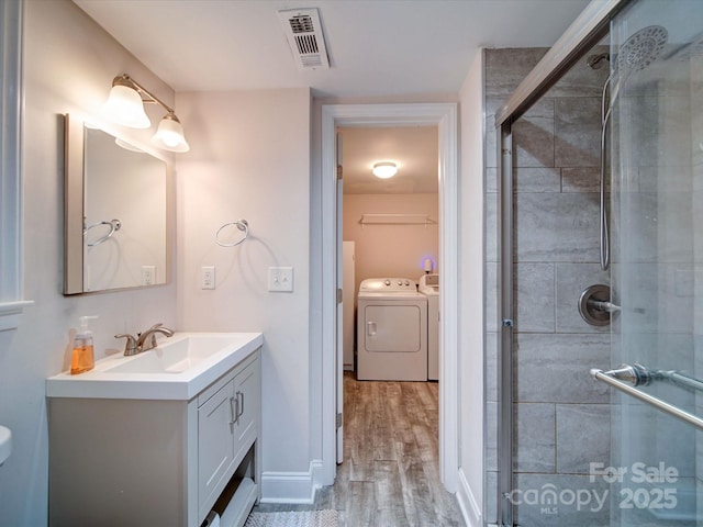 full bathroom featuring visible vents, a shower stall, wood finished floors, vanity, and separate washer and dryer