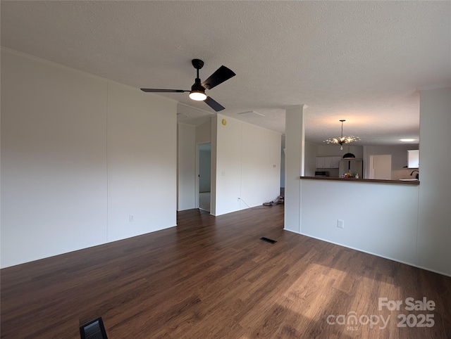 unfurnished living room featuring ceiling fan with notable chandelier, visible vents, dark wood-style flooring, and a textured ceiling