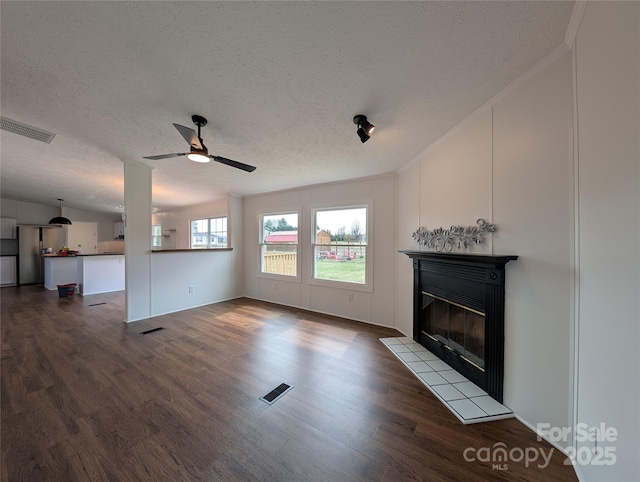 unfurnished living room with visible vents, a tile fireplace, ceiling fan, and wood finished floors