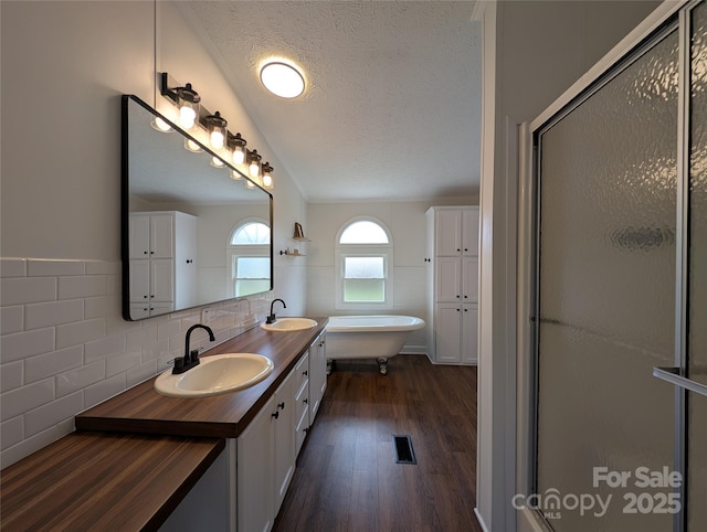 bathroom featuring a sink, a freestanding tub, a textured ceiling, and a shower stall