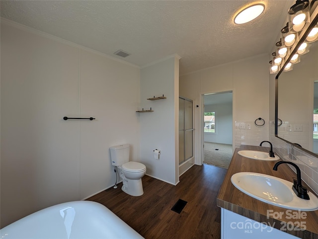 bathroom with a textured ceiling, wood finished floors, visible vents, and a sink