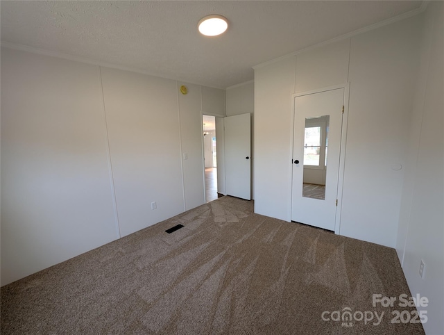 empty room featuring crown molding and carpet