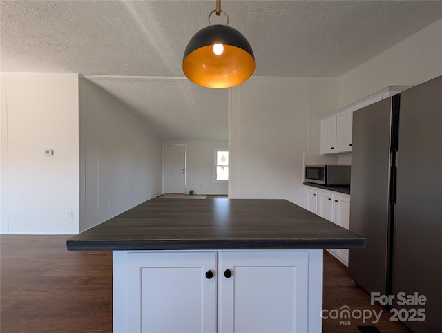 kitchen with a kitchen island, white cabinetry, appliances with stainless steel finishes, a textured ceiling, and dark wood-style flooring