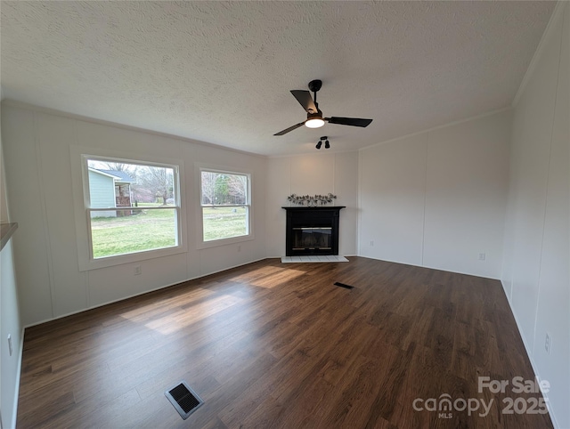 unfurnished living room featuring dark wood finished floors, visible vents, ceiling fan, and a decorative wall