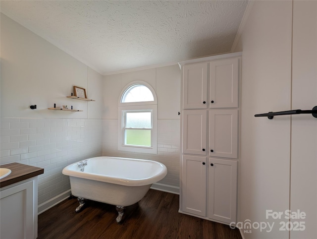 bathroom featuring vanity, a freestanding tub, tile walls, a textured ceiling, and wood finished floors