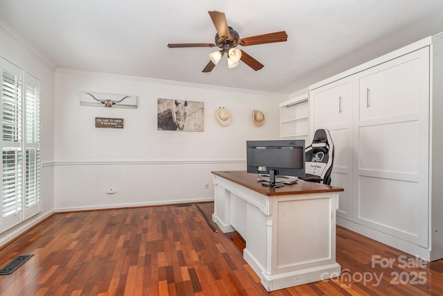 unfurnished office featuring dark wood-style floors, baseboards, a ceiling fan, visible vents, and ornamental molding