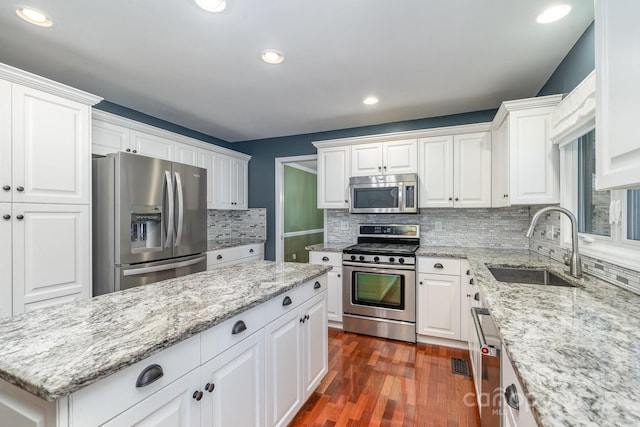 kitchen with a sink, dark wood-type flooring, appliances with stainless steel finishes, and white cabinets