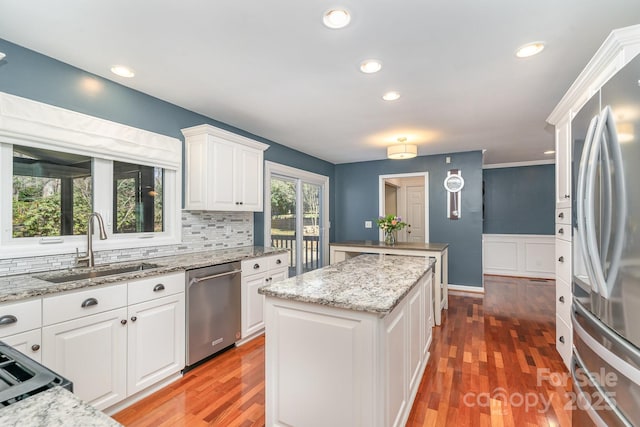 kitchen with light wood-style flooring, a sink, a center island, appliances with stainless steel finishes, and white cabinets