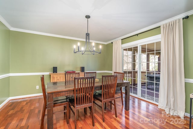 dining room featuring baseboards, a notable chandelier, wood finished floors, and crown molding