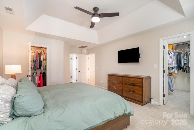 bedroom featuring visible vents, a spacious closet, a closet, light carpet, and a raised ceiling