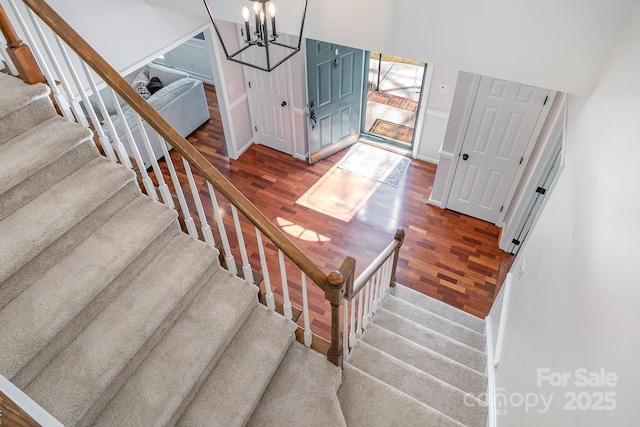 staircase featuring baseboards, a notable chandelier, and wood finished floors