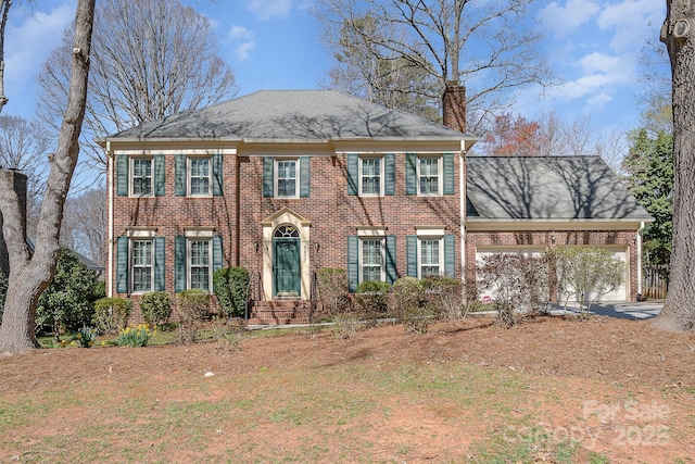 view of front of property featuring an attached garage, brick siding, and a chimney