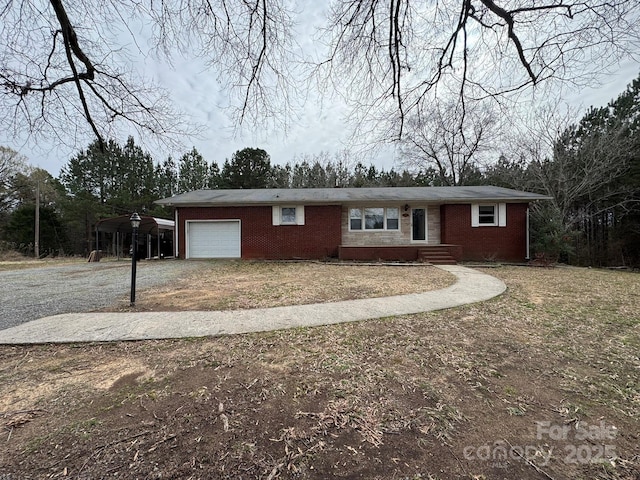 single story home featuring a carport, a garage, brick siding, and dirt driveway