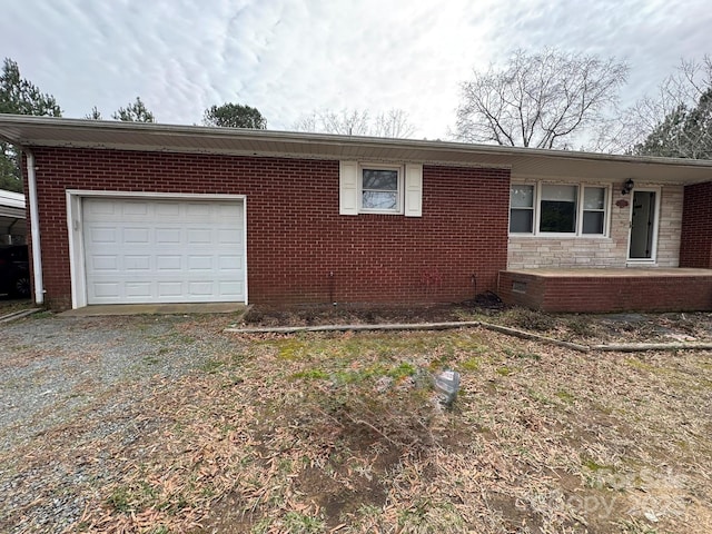 view of side of property featuring crawl space, driveway, brick siding, and an attached garage