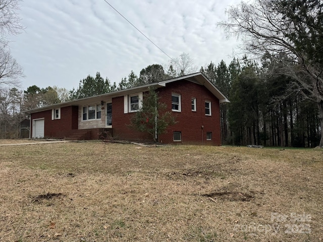 exterior space featuring brick siding, a yard, and a garage