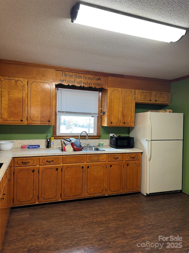 kitchen featuring dark wood-style flooring, freestanding refrigerator, a sink, light countertops, and black microwave