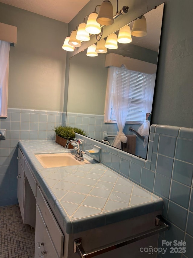 bathroom featuring vanity, wainscoting, an inviting chandelier, tile patterned floors, and tile walls