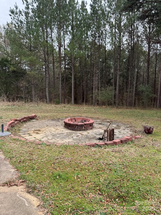 view of yard featuring a fire pit and a view of trees