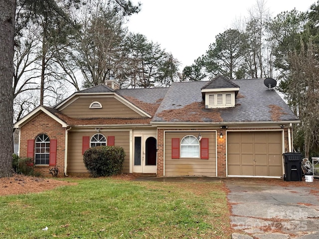 view of front of house with a front lawn, aphalt driveway, french doors, an attached garage, and brick siding