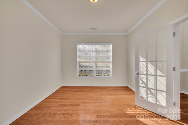 empty room featuring visible vents, baseboards, light wood-style floors, and crown molding