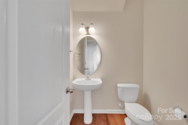 bathroom featuring toilet, baseboards, and wood finished floors