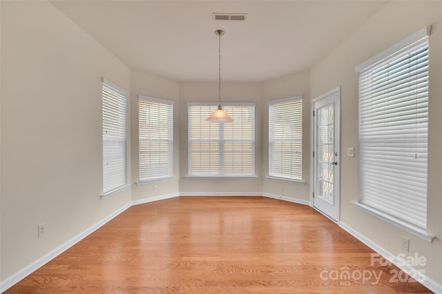 unfurnished dining area with visible vents, plenty of natural light, baseboards, and light wood-style floors