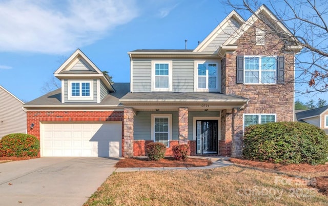12724 Hunting Birds Ln, Charlotte, NC 28278 - view of front of property with driveway, covered porch, an attached garage, stone siding, and a front lawn