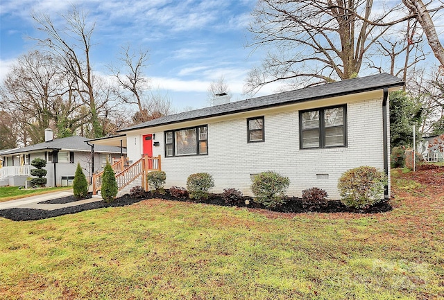 view of front of home featuring crawl space, brick siding, a chimney, and a front yard