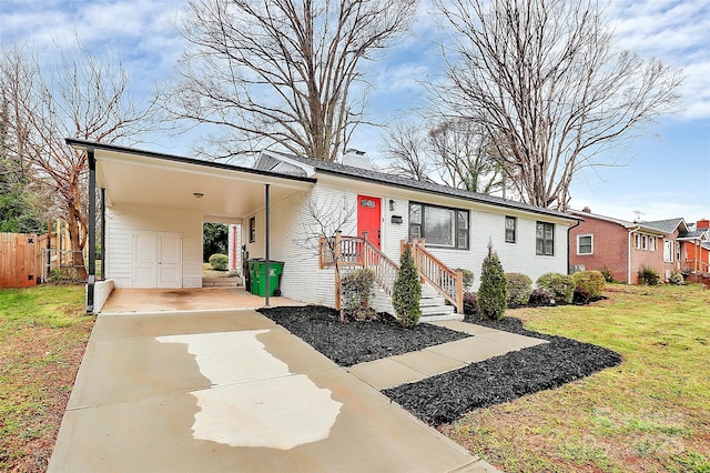 view of front of home with driveway, a carport, fence, a front yard, and brick siding