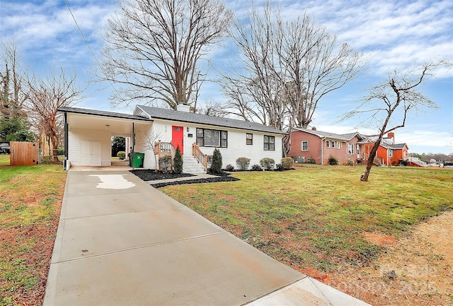 view of front of property with a front lawn, driveway, an attached carport, fence, and brick siding