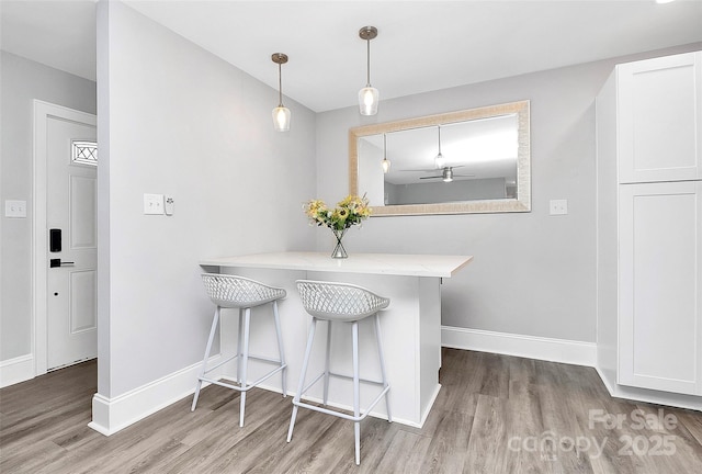 dining room with a ceiling fan, wood finished floors, and baseboards