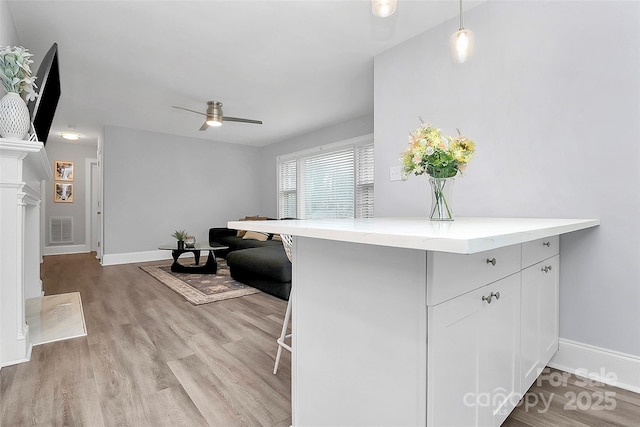 kitchen featuring light wood-type flooring, visible vents, a kitchen bar, and a ceiling fan