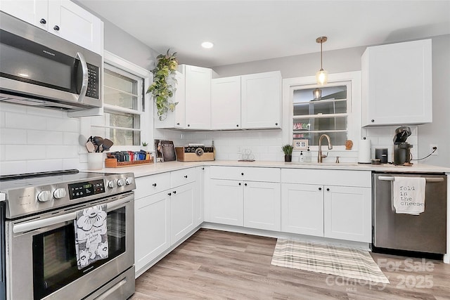 kitchen featuring a sink, light countertops, white cabinets, appliances with stainless steel finishes, and backsplash