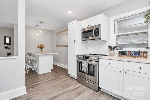 kitchen featuring light countertops, decorative backsplash, light wood-style floors, white cabinets, and stainless steel appliances