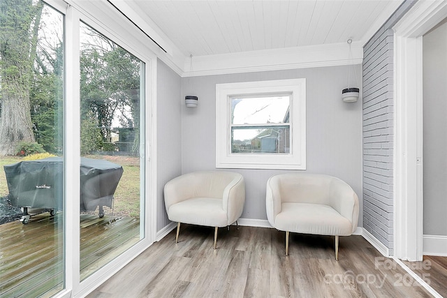 sitting room with baseboards, wood finished floors, and ornamental molding