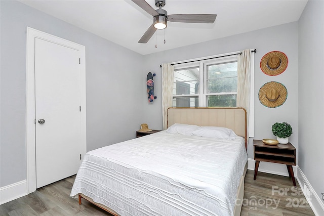 bedroom with a ceiling fan, baseboards, and wood finished floors