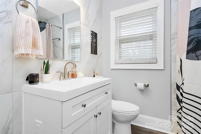 bathroom with a shower with curtain, toilet, wood finished floors, baseboards, and vanity